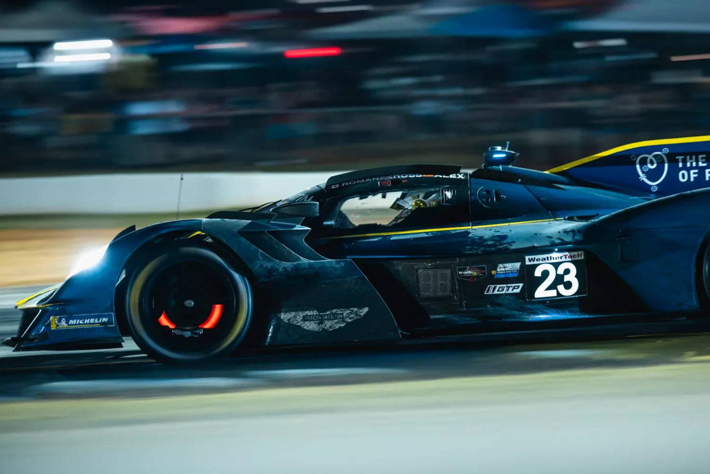 Number 23 Aston Martin Valkyrie racing at night with glowing front brake disc