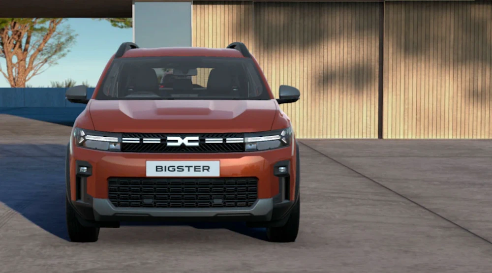 Terracotta Dacia Bigster viewed head-on outside a modern building