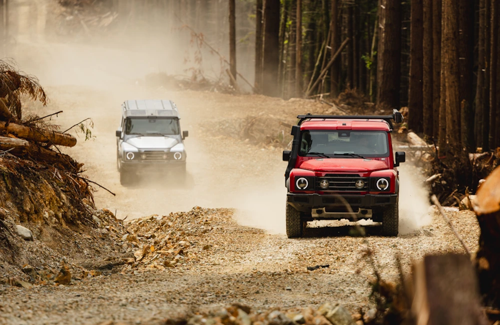 Two INEOS Grenadiers travelling along a forest trail