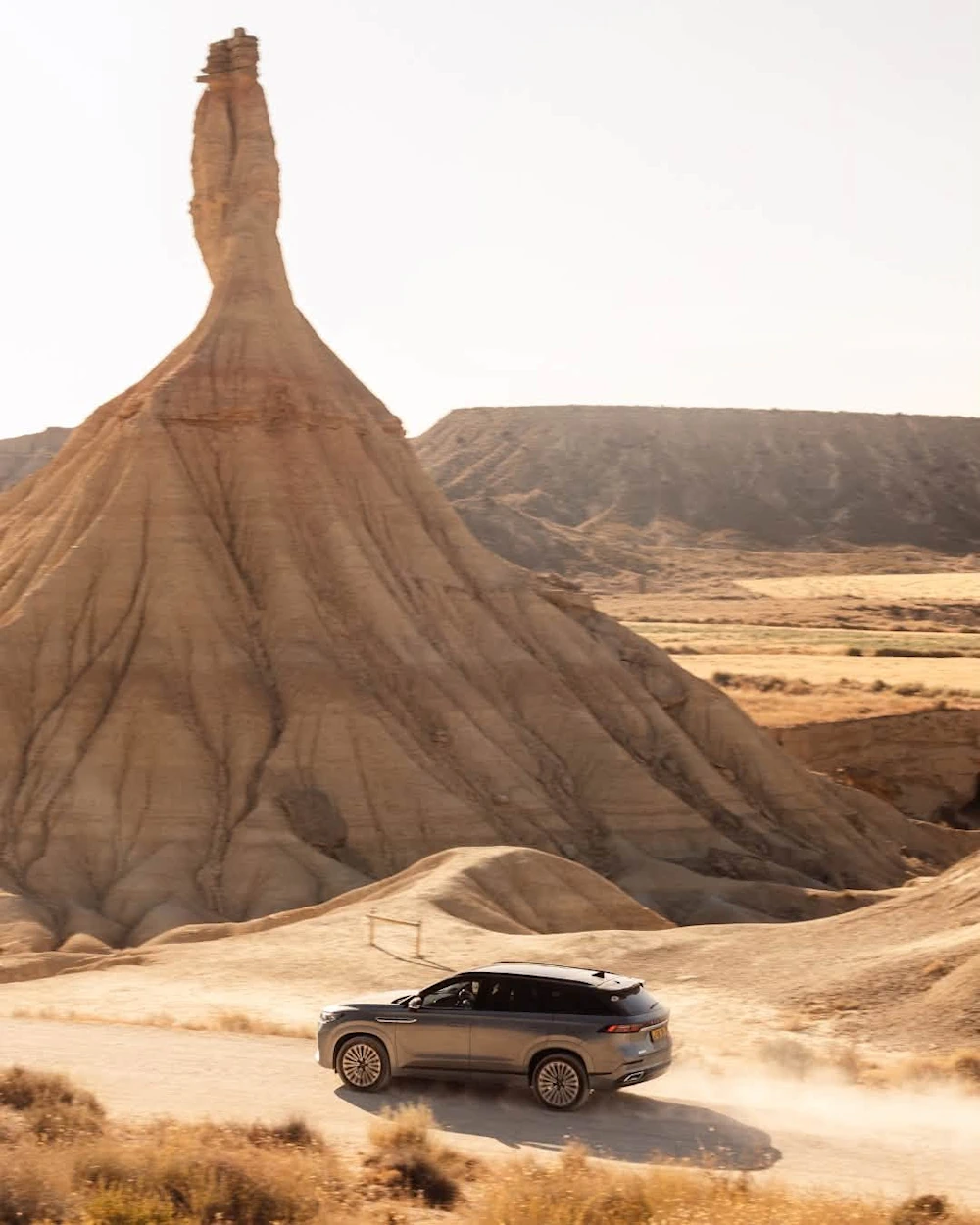 JAECOO 8 travelling along a dusty track below a rock formation