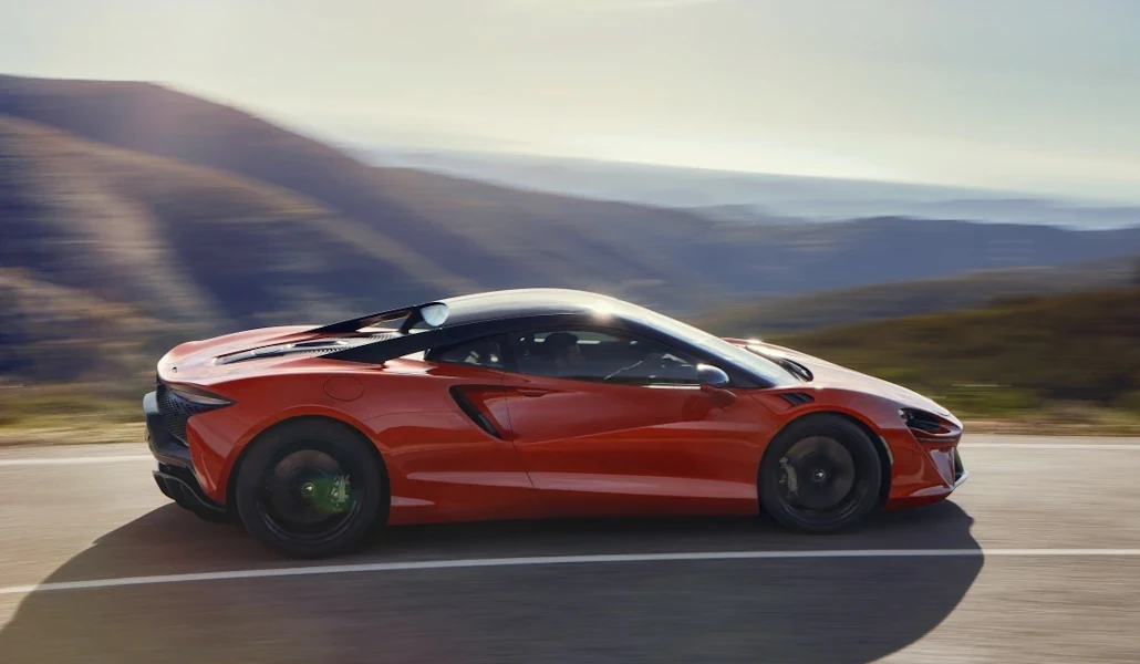 Red McLaren Artura driving on a road in Grange model photography