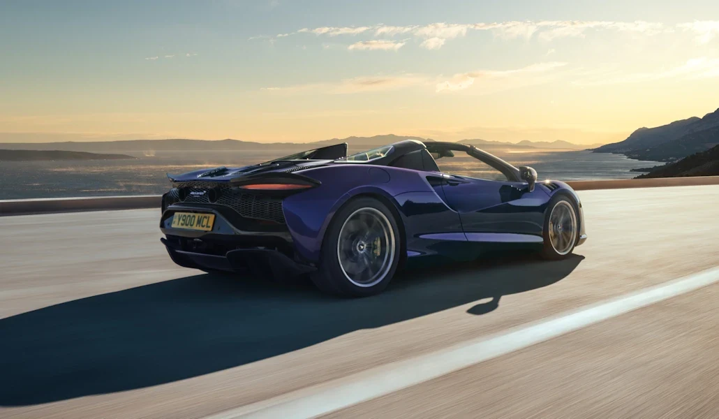Blue McLaren Artura Spider driving with its roof open
